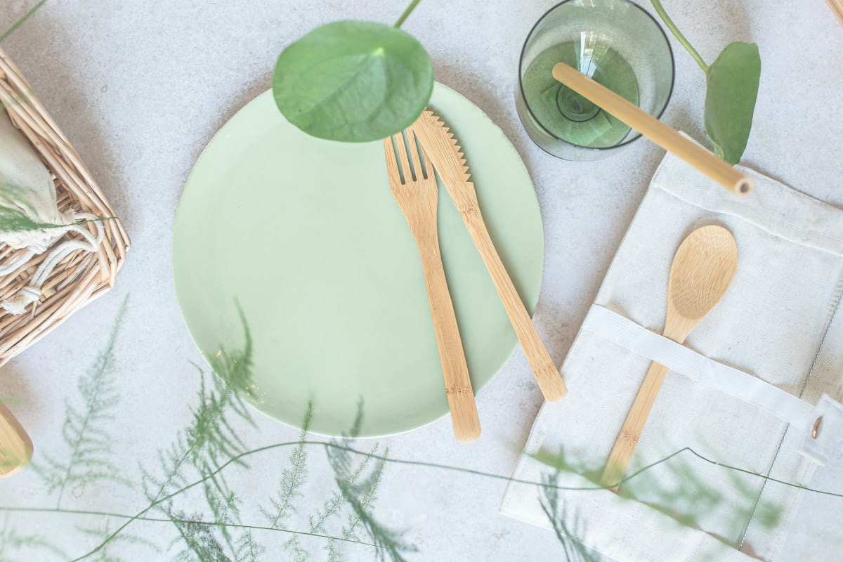 Green plate with wooden utensils on a table
